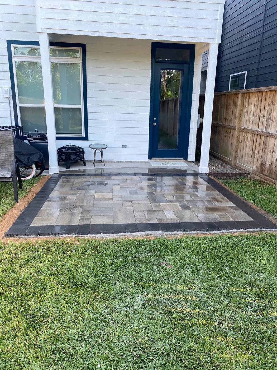Small backyard paver patio with a dark border, next to the back door